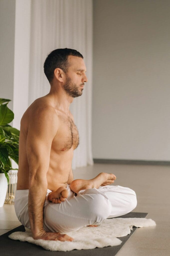 a man with a bare torso does yoga in a fitness room. the concept of a healthy lifestyle