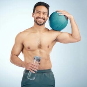 Fitness, water bottle and medicine ball with a sports man in studio for health or natural body. Por