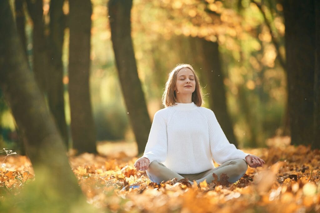  Young woman is doing yoga in the autumn park