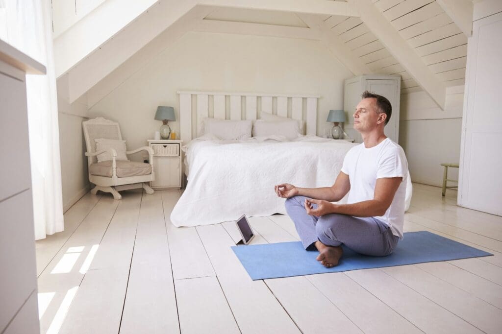 Man With Digital Tablet Using Meditation App In Bedroom