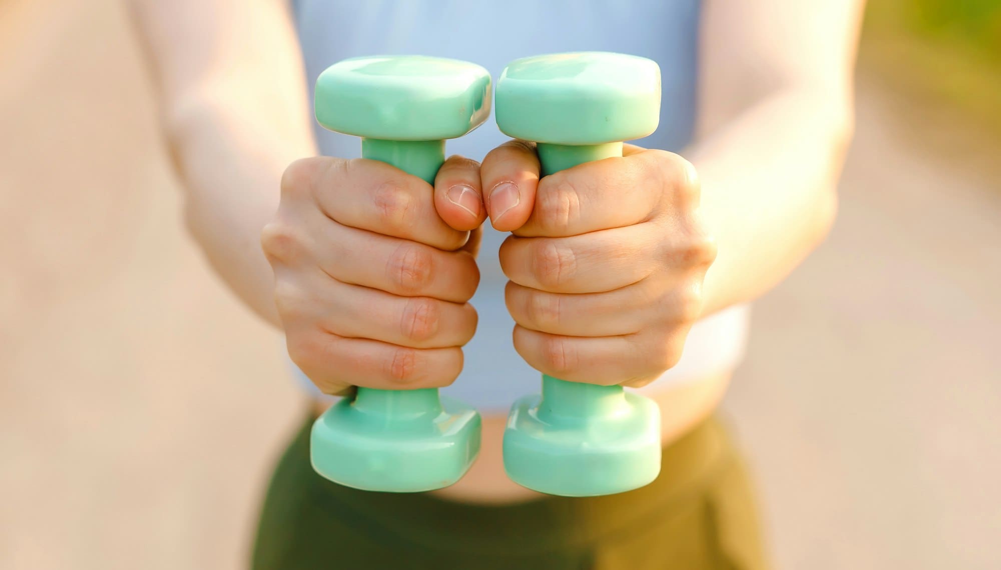 Close up of female hands holding dumbbells while working out