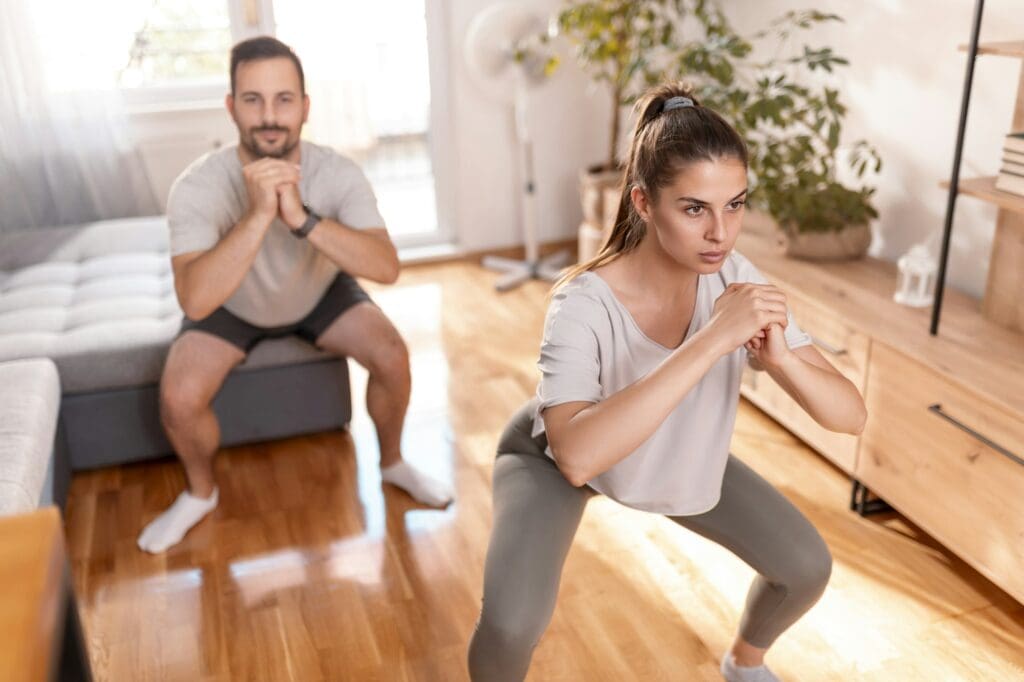 Couple doing squats while working out together at home