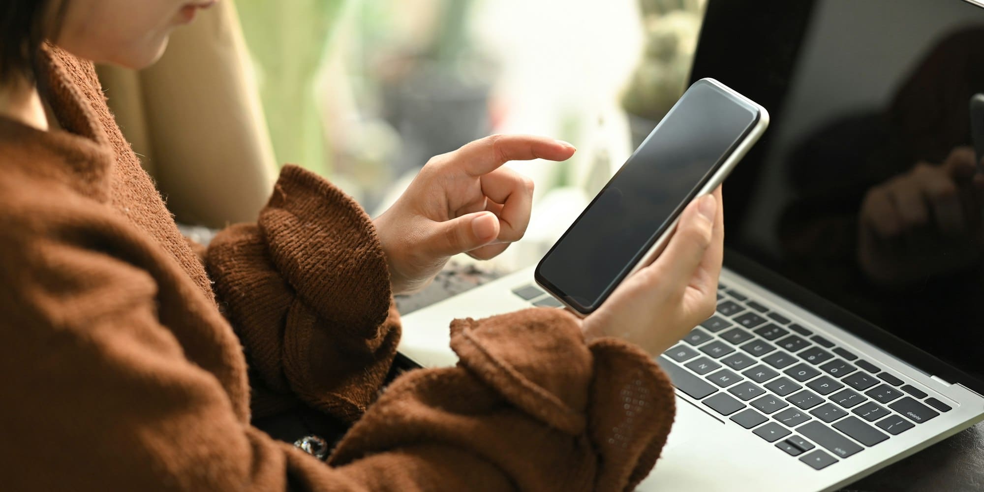 Photo of beautiful woman relaxing on her holidays by using a black blank screen smartphone.