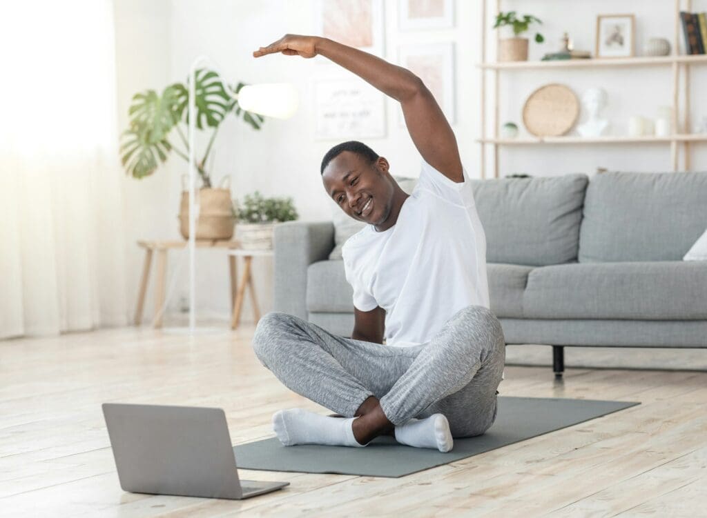 man stretching at home, using laptop