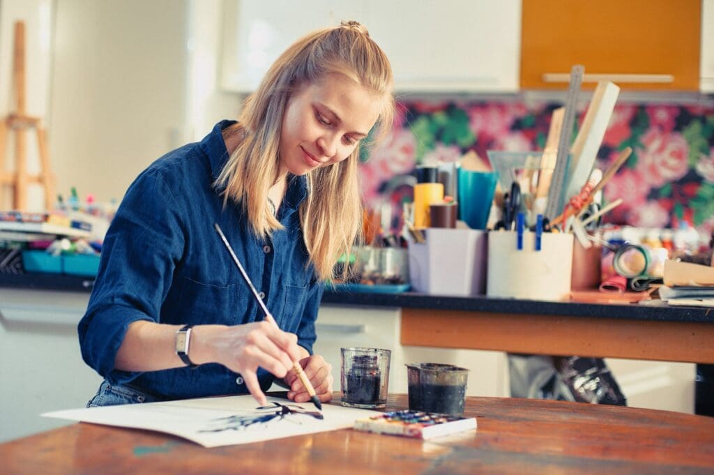 Young Woman Artist Working On Painting 