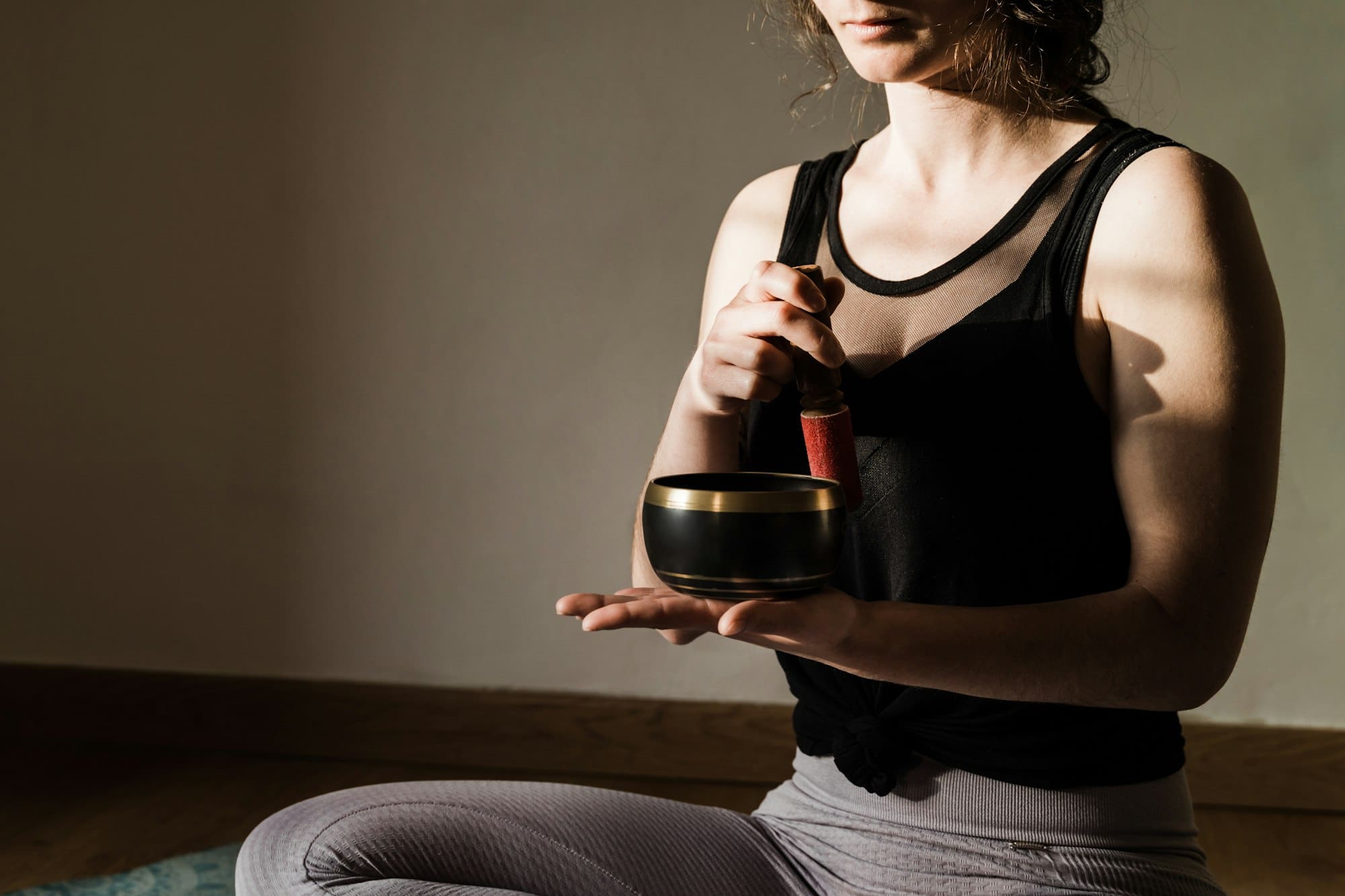 Young woman doing yoga meditation while singing tibetan bowl - Focus on holistic healer instrument